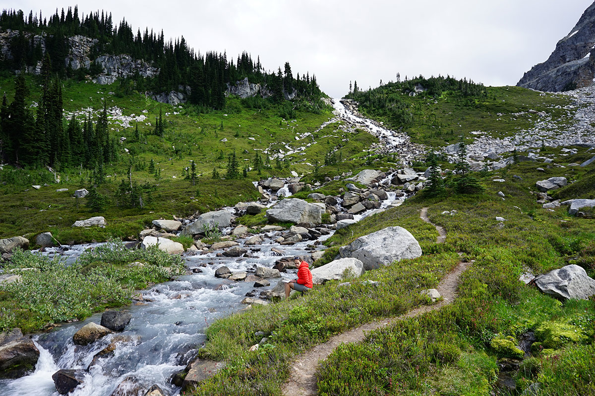 Emilie Blevins sits beside a rocky stream in the mountains