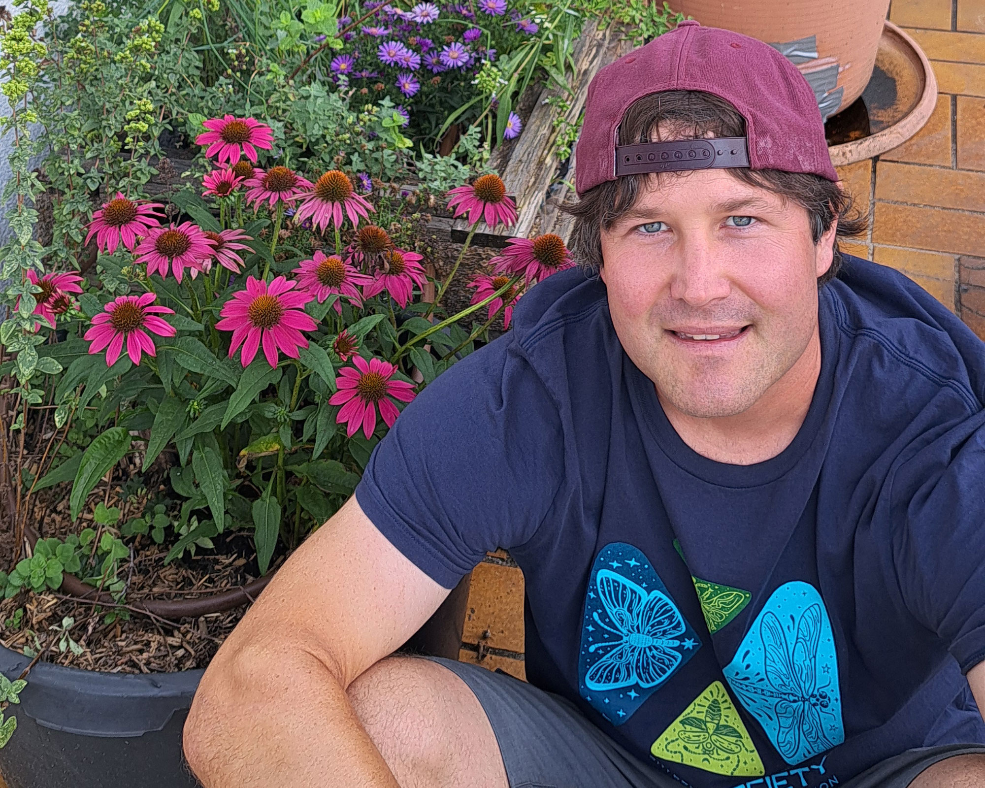 Jochen wearing Xerces Society shirt sitting in front of blooming flowers in several containers