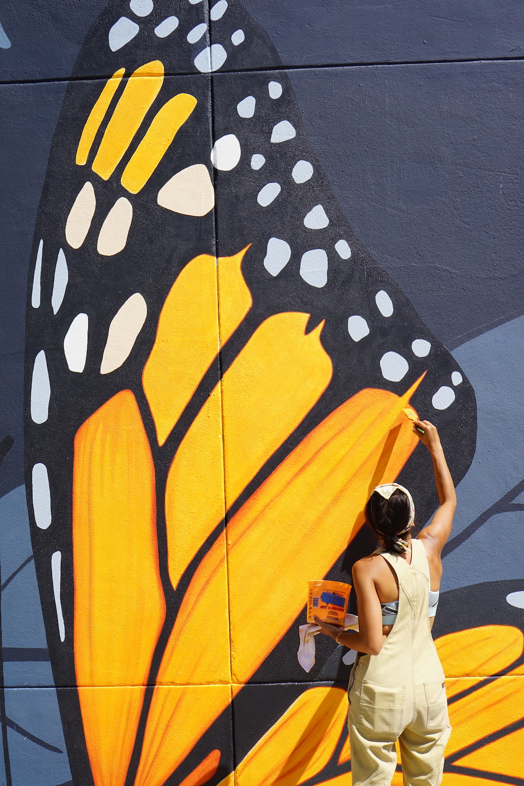 Artist Jane Kim of Ink Dwell studio paints the wing of a giant monarch butterfly, part of the Midnight Dream mural in downtown Orlando, Florida.