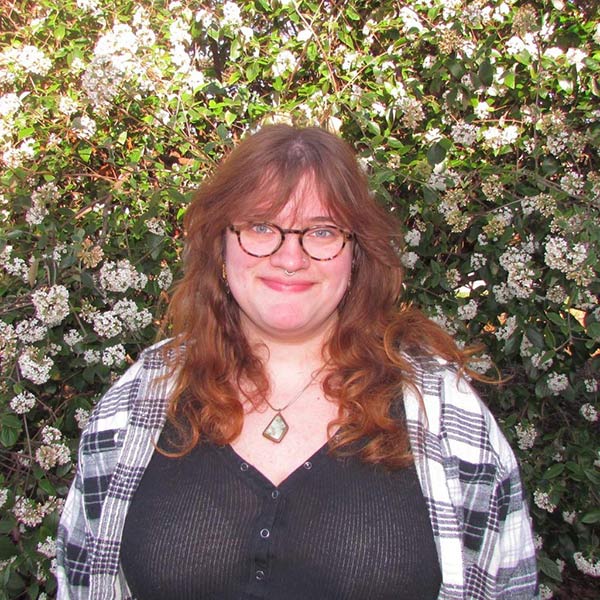 Holly Myers standing in front of a flowering bush