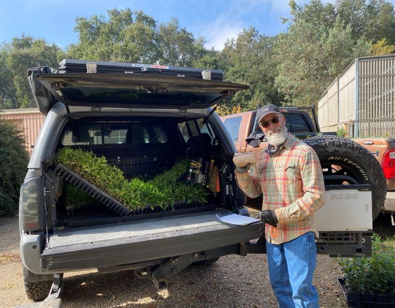 Man poses with California Habitat Kit plants in truck during pickup. Credit: Angela Laws.