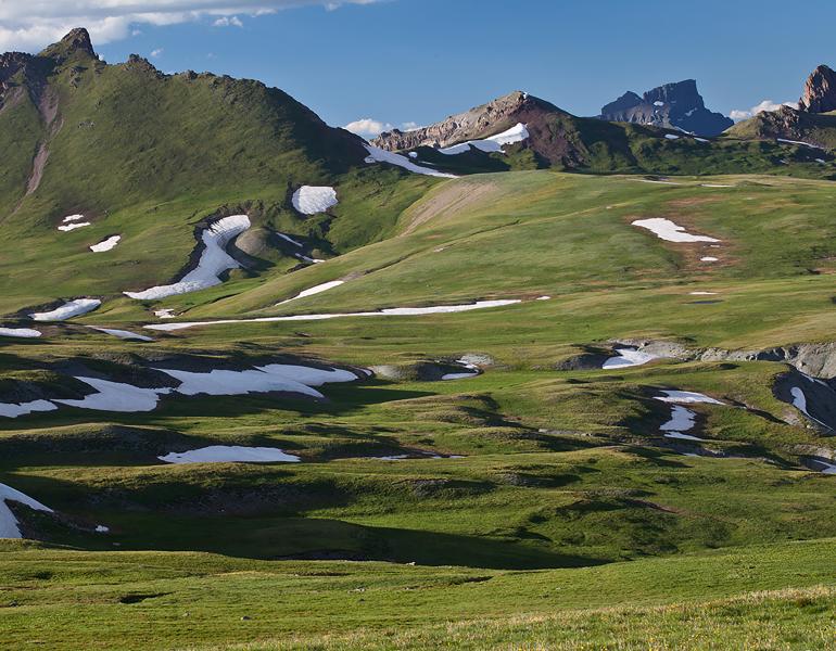 Patches of snow remain all year on the green grass slopes of the San Juan Mountains of Colorado