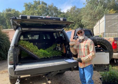 Man poses with California Habitat Kit plants in truck during pickup. Credit: Angela Laws.