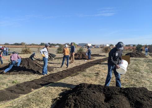 Volunteers apply cardboard, compost, and mulch to the ground to prepare for habitat restoration at a vineyard