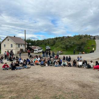 Over a hundred students circle around a speaker, listening to instructions for the day