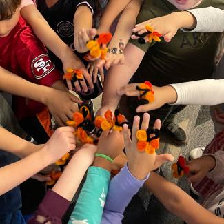 Group of students with pipe cleaner monarch rings on hands