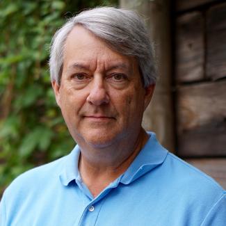 Ted Burk, an older white man with grey hair, smiling gently