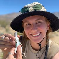 Jenae McCarthy outside, posing with a reptile